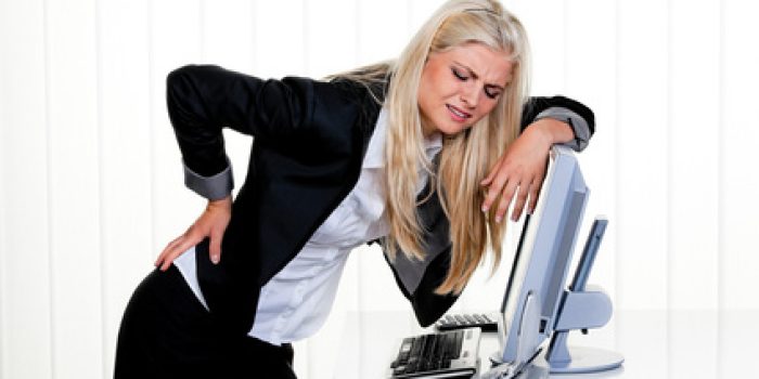 Frau mit Schmerzen im Rücken im Büro